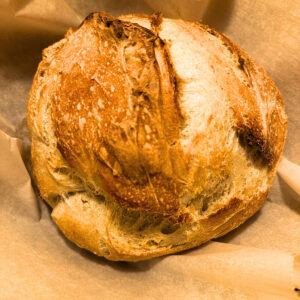 freshly baked, homemade sour dough bread loaf. Made in Dutch oven on parchment paper.