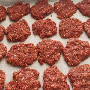 handmade Italian sausage patties on parchment paper and cookie sheet