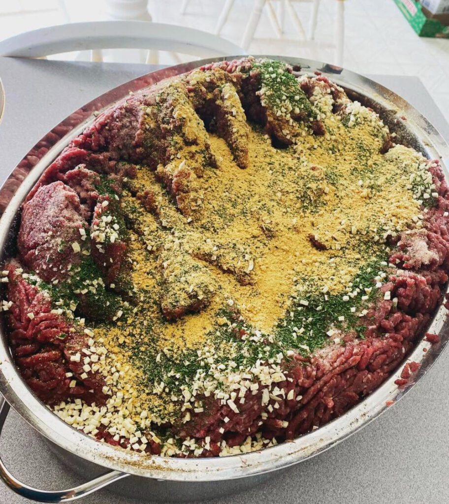 ground meat and ingredients in a roaster pan ready to be mixed into Italian sausage